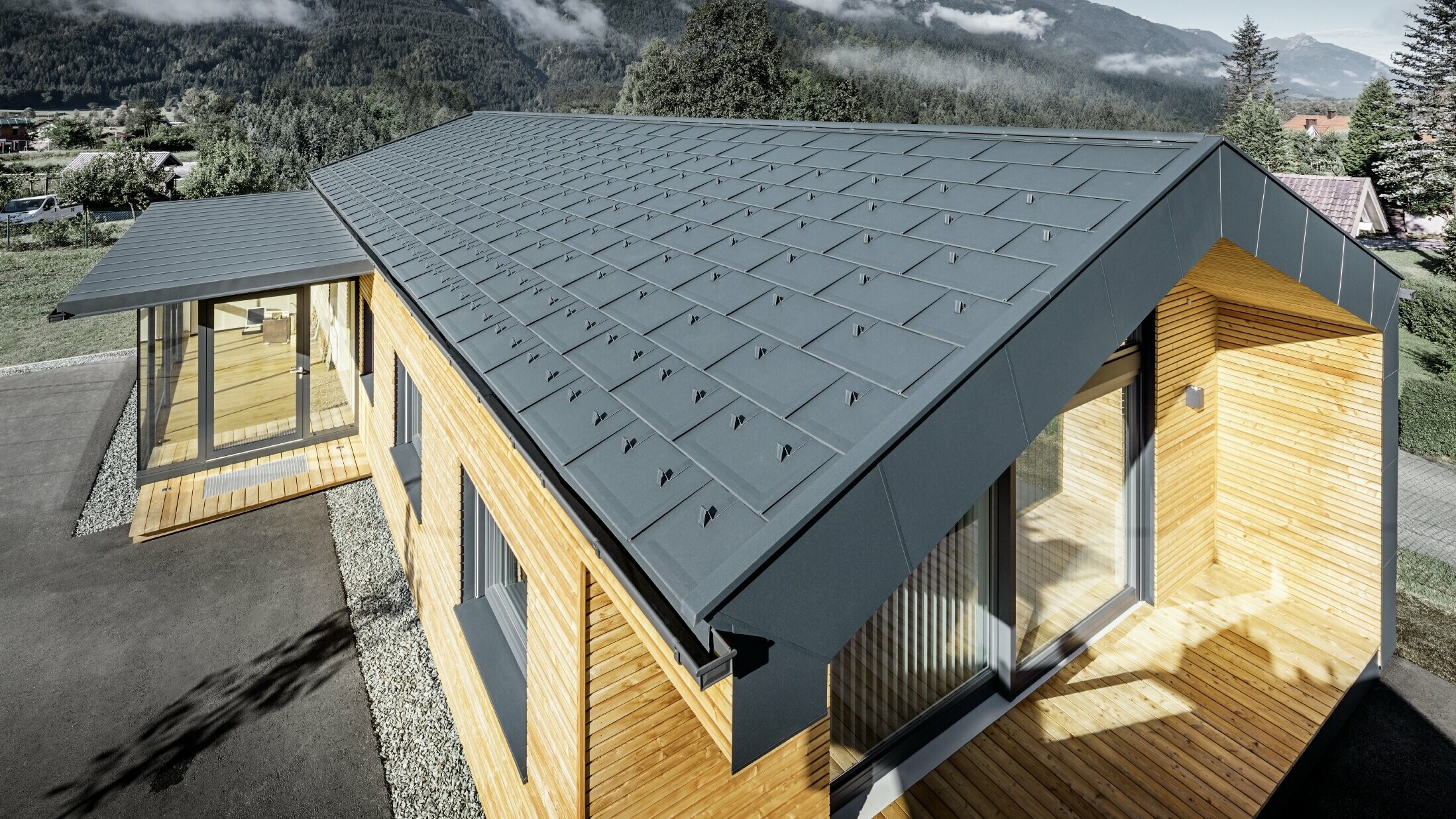 Nová administrativní budova firmy Holzbau Faltheiner s fasádou z modřínového dřeva, velkorysými prosklenými plochami a střechou PREFA v antracitové barvě.