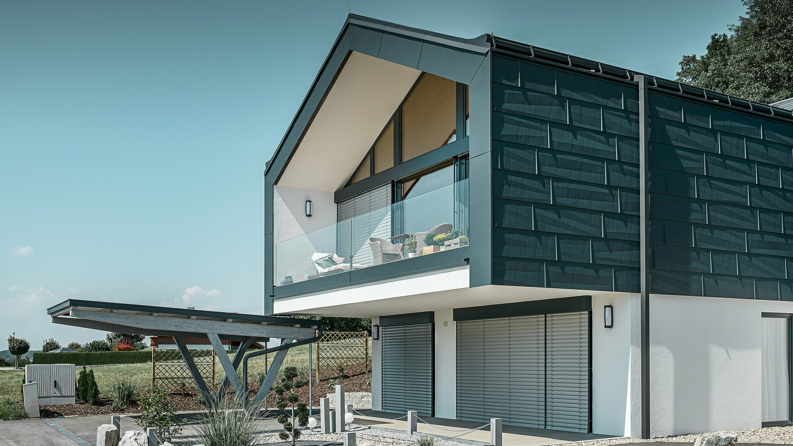 Fassadenverkleidung des Obergeschoßes mit dem PREFA Fassadenpaneel FX.12 in P.10 Anthrazit. Als Ablaufrohr dient das robuste PREFA Quadratrohr.