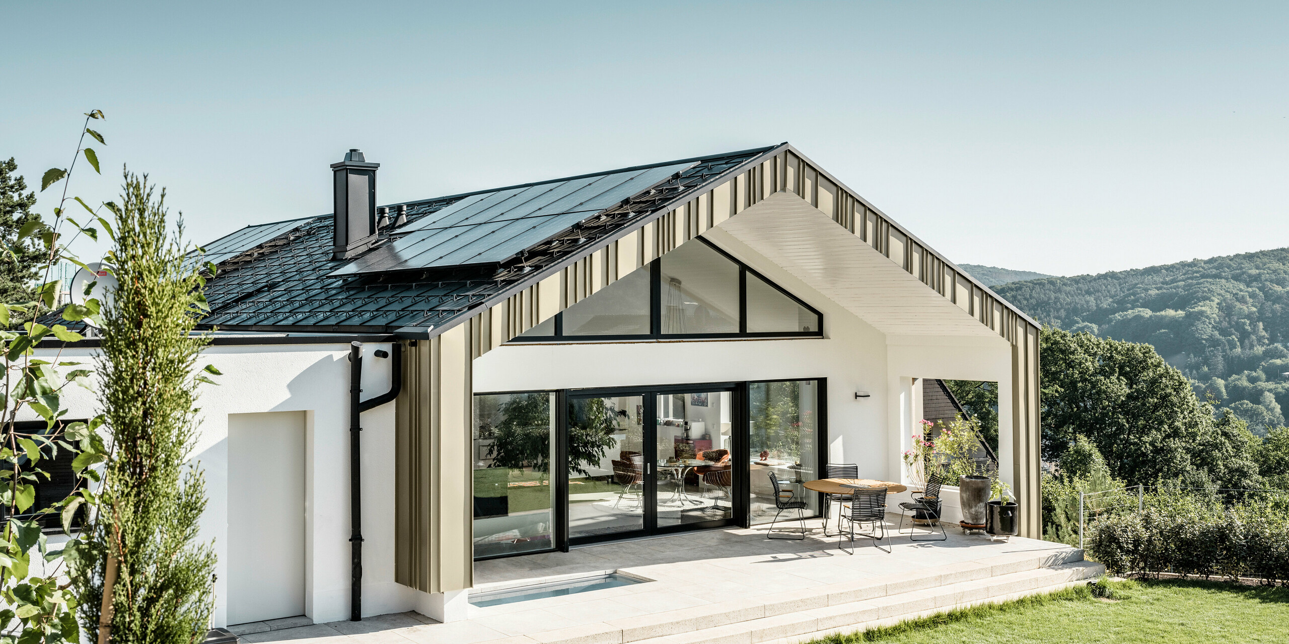 Kombinace antracitové střešní krytiny a světle bronzové fasády