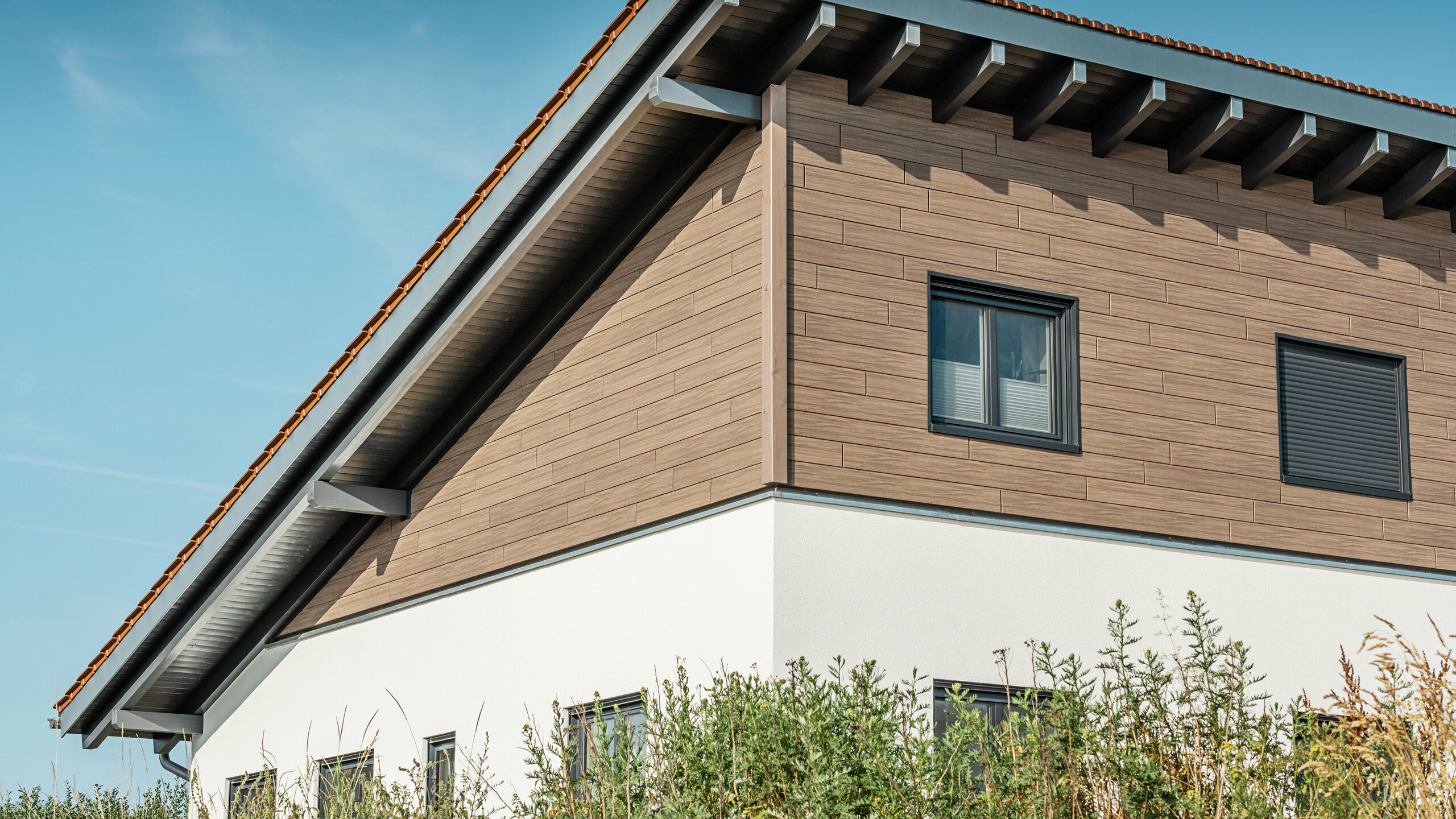 Dům s pultovou střechou a kombinovanou fasádou z hliníkových lamel Siding a bílé omítkové fasády