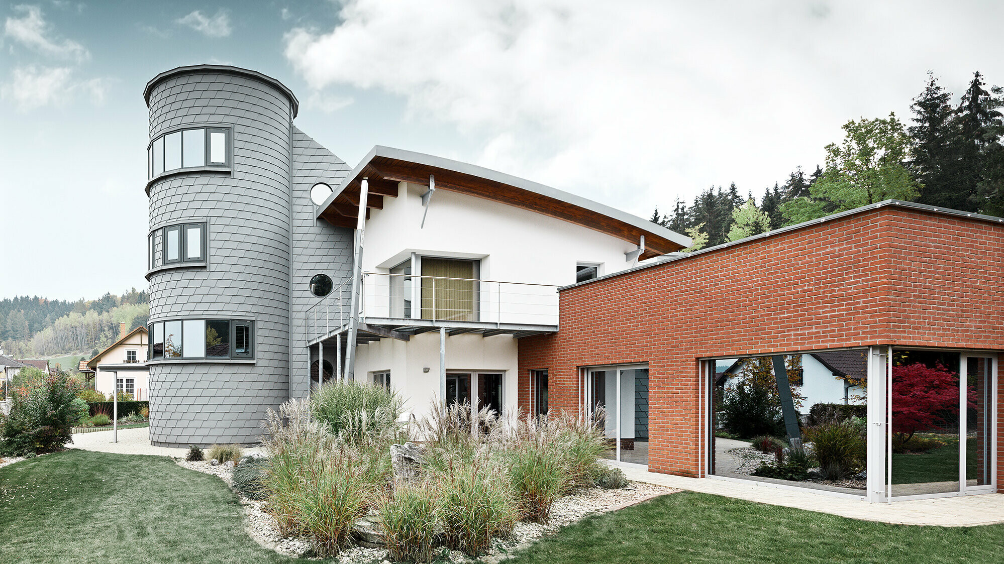 Rodinný dům s věžovou přístavbou, kulatá věž je obložena fasádními šindeli PREFA v barvě patina šedá 