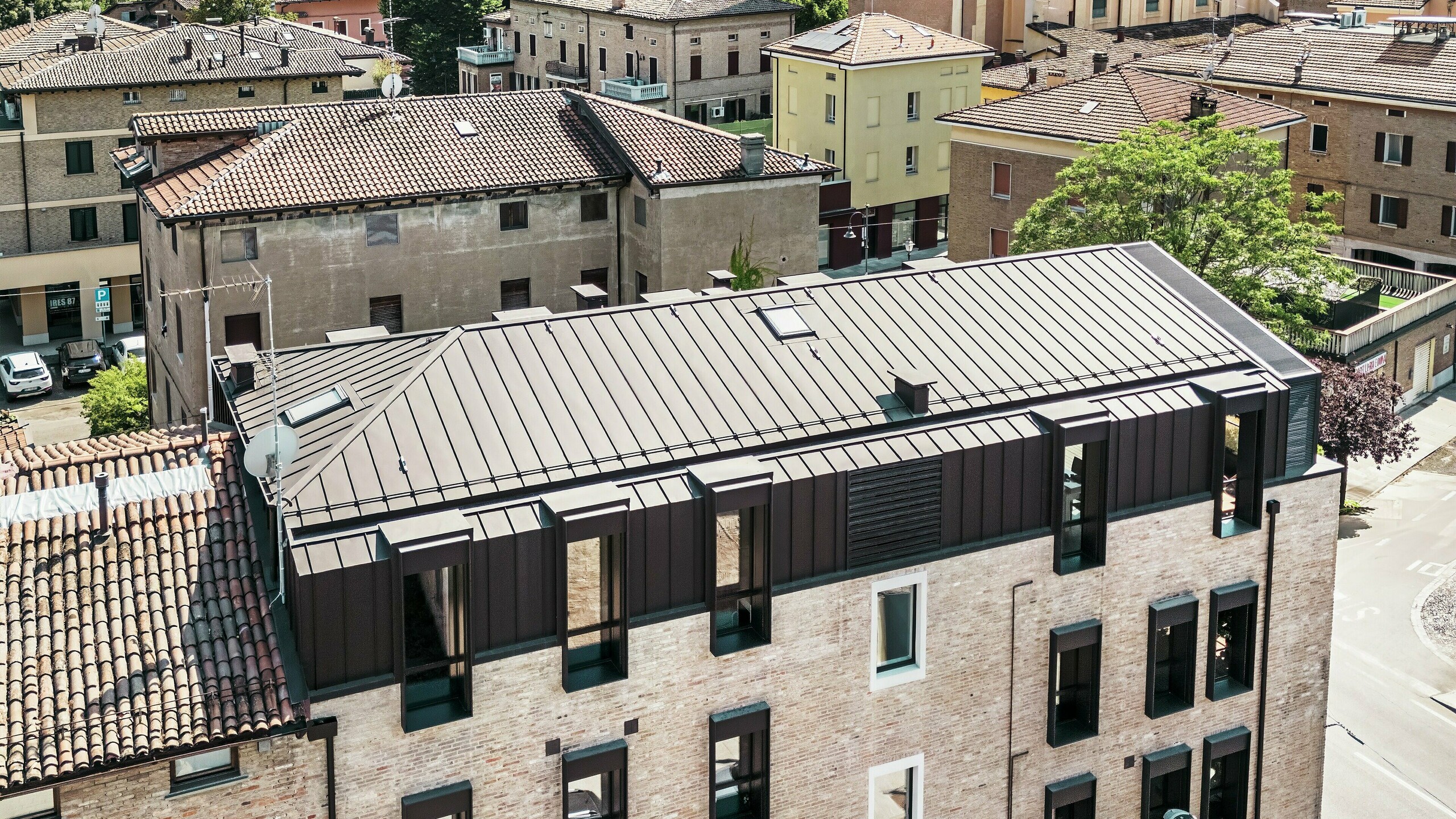 Modernizovaný cihlový dům v Itálii s hliníkovou střechou z drážkované krytiny PREFALZ v barvě P.10 oříškové – estetická kombinace tradiční cihlové architektury a moderního, odolného střešního řešení