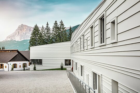 Reines Licht, klare Linien: Die Fassade der „Tempesti“-Kaserne in Südtirol demonstriert eindrucksvoll, wie sich modernes Design harmonisch in die Berglandschaft einfügen kann. Die horizontalen PREFALZ-Leisten in der Farbe P.10 Prefaweiß reflektieren das Sonnenlicht, verbessern das Raumklima und überzeugen durch ihre robuste, langlebige Qualität. Sie sind ein starkes Beispiel für durchdachte Militärarchitektur mit Aluminium.