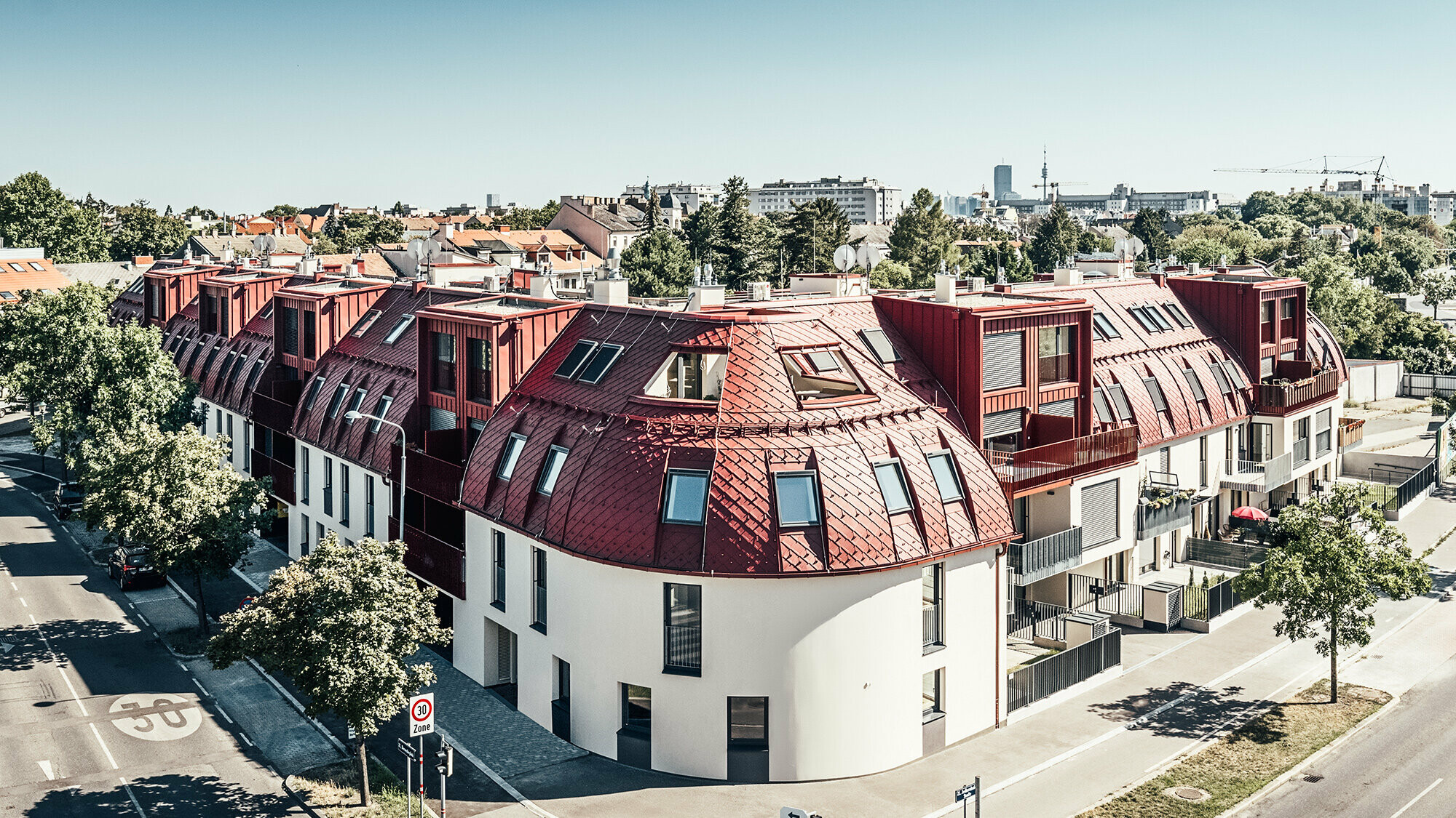 Pohled z ulice na rezidenční komplex Schöneck se zaoblenou střechou navrženou architekty schneider+schumacher