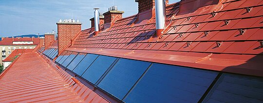 Detailní pohled na PREFA falcované střešní šindele se sněhovými zarážkami  v cihlově červené barvě na střechách bytových domů Hugo-Breitner-Hof.