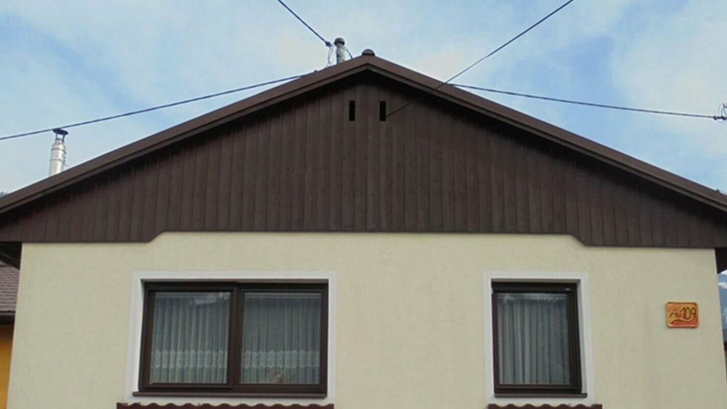 Stav před sanací fasády štítu za použití PREFA Sidings, žlutá omítková fasáda, zvětralé dřevo