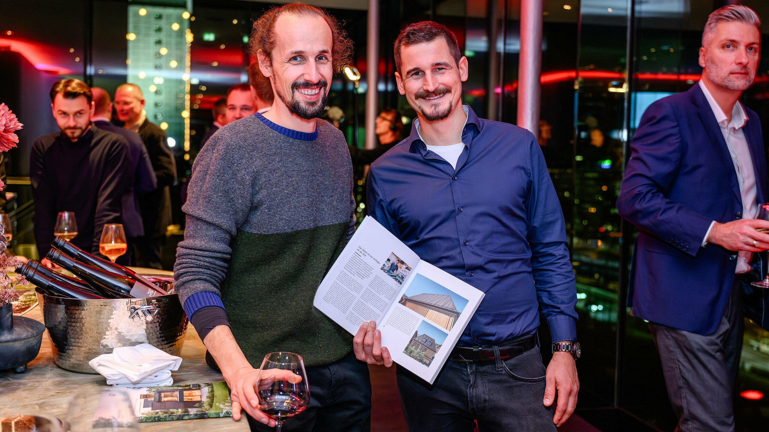 Zářící tváře na prezentaci PREFARENZEN 2026: Dva účastníci projektu hrdě představují svůj projekt v nové architektonické knize PREFA. Vila na obrázku kombinuje přírodní vzhled dřeva s PREFALZ – ukázkovým příkladem moderního materiálového kontrastu a trvalé estetiky. Akce v k47.wien spojuje design, architekturu a networking na nejvyšší úrovni. Hliníkové produkty PREFA zde předvádějí svou plnou sílu: odolné vůči povětrnostním vlivům, kreativně všestranné a udávají trendy pro progresivní stavební projekty. Večer plný hrdosti, výměny názorů a inovací.