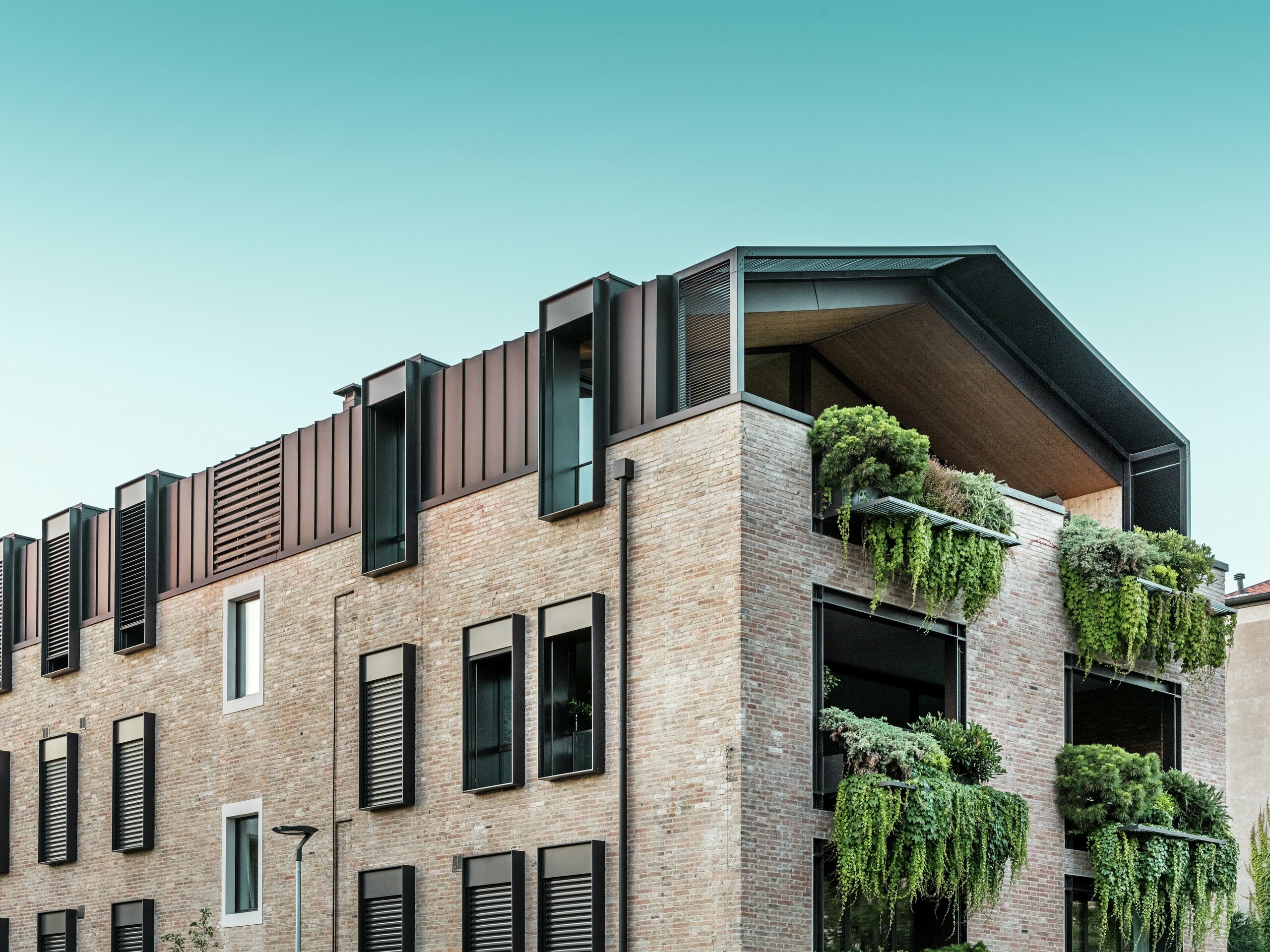 Udržitelný obytný dům v Itálii s hliníkovou střechou z PREFALZ v barvě P.10 oříškové a visutými zahradami na jižní fasádě – klimaticky aktivní architektura s cihlami a zelení.