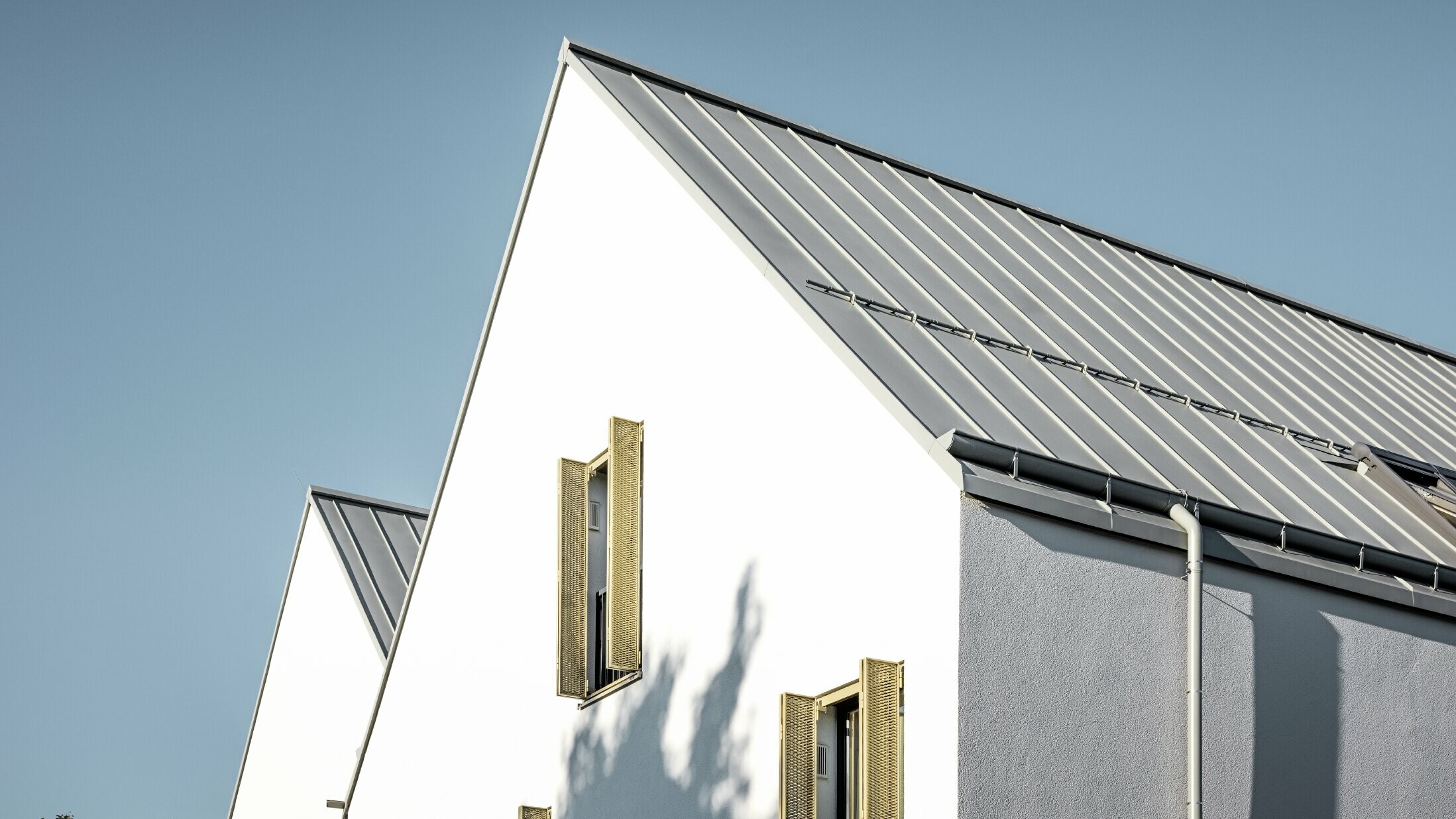 Sedlová střecha bez přesahu, pokrytá svitkovým plechem PREFALZ v provedení P.10 zinkově šedá s nástřešním žlabem PREFA