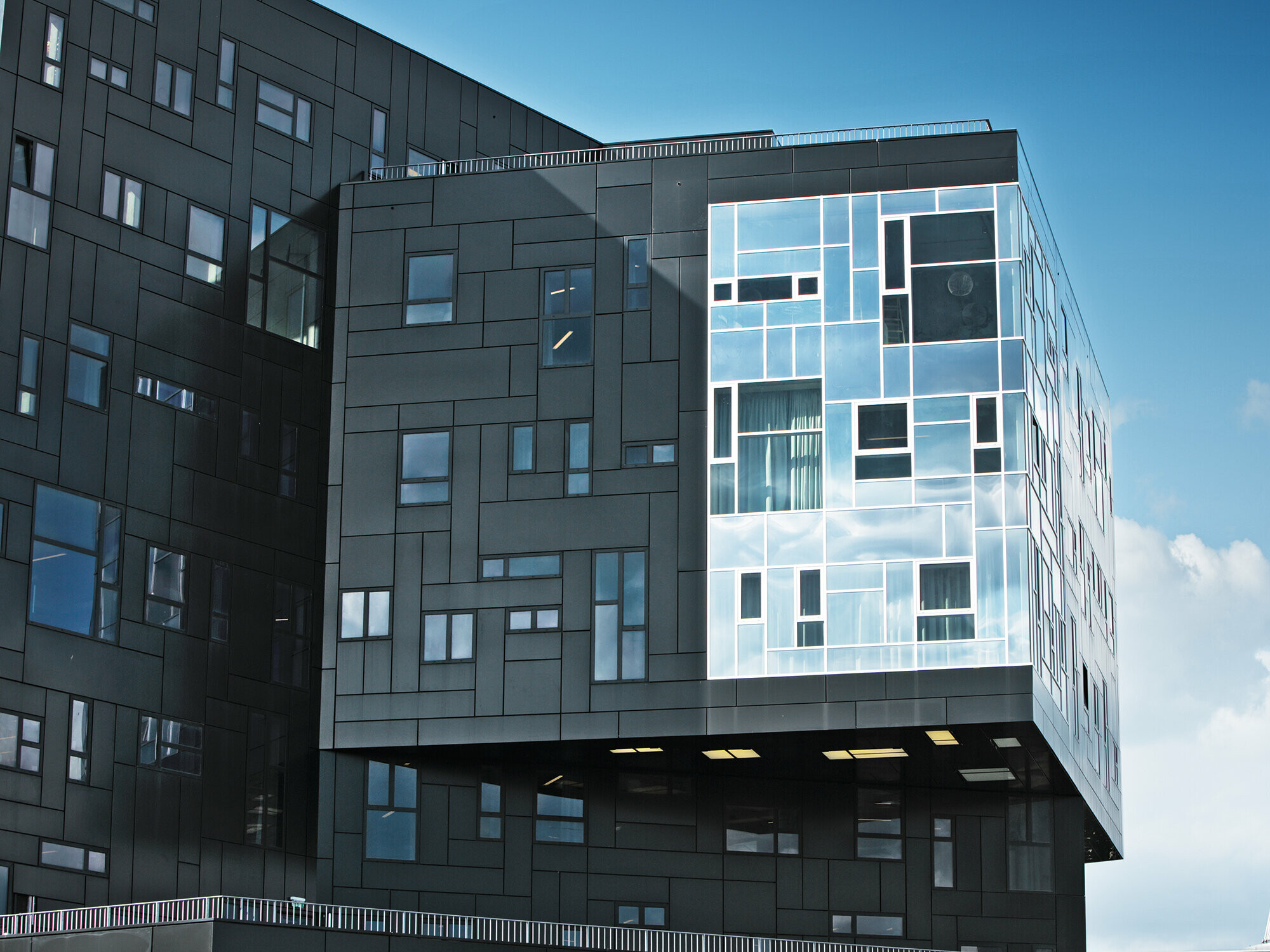 Záběr z WU Executive Academy se zaměřením na fasádu z hliníkových kompozitních desek PREFA v tmavě černé barvě a lesklou část oken.