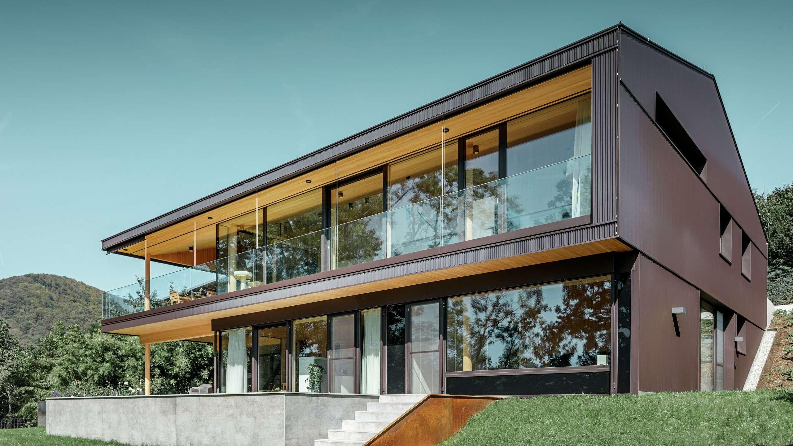 Moderní rodinný dům s velkými okny do zahrady a fasádou z Zackenprofil (lisovaného pilového profilu) v barvě na přání - hnědé.