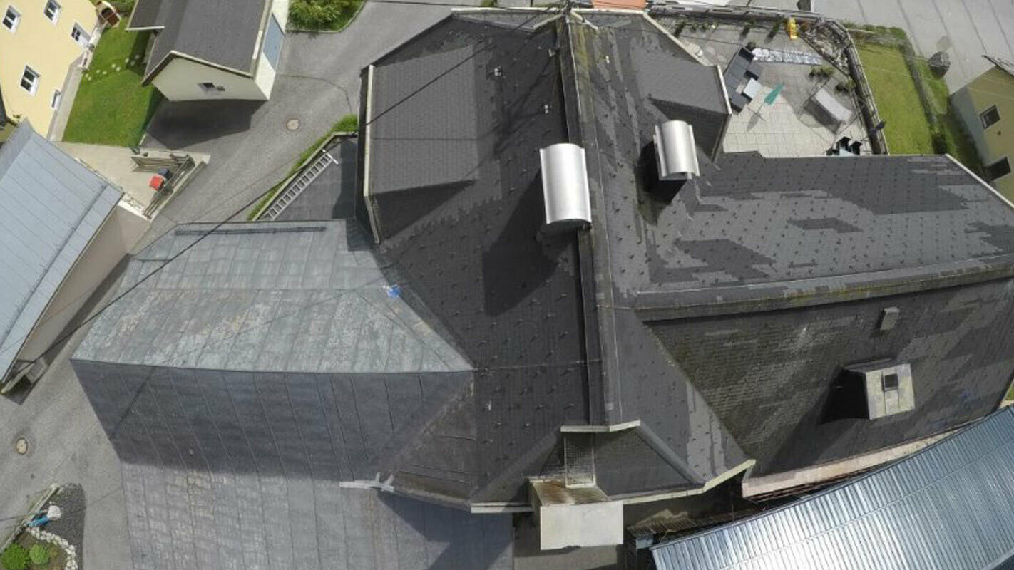 Pohled z ptačí perspektivy na starou střechu s mnoha detaily - úžlabími, vikýři a komíny. Stará střešní krytina byla několikrát opravována a je skvrnitá