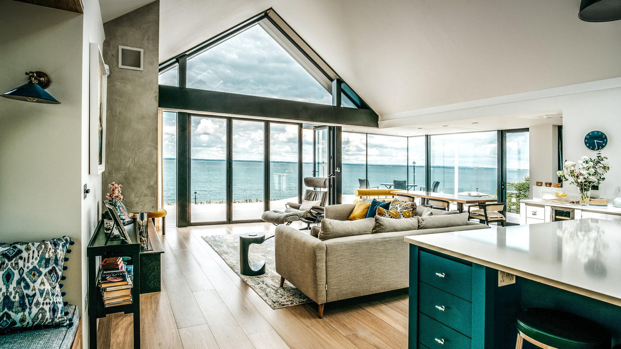 Pohled z kuchyňského bloku do extravagantního obývacího prostoru s velkorysým proskleným čelem.