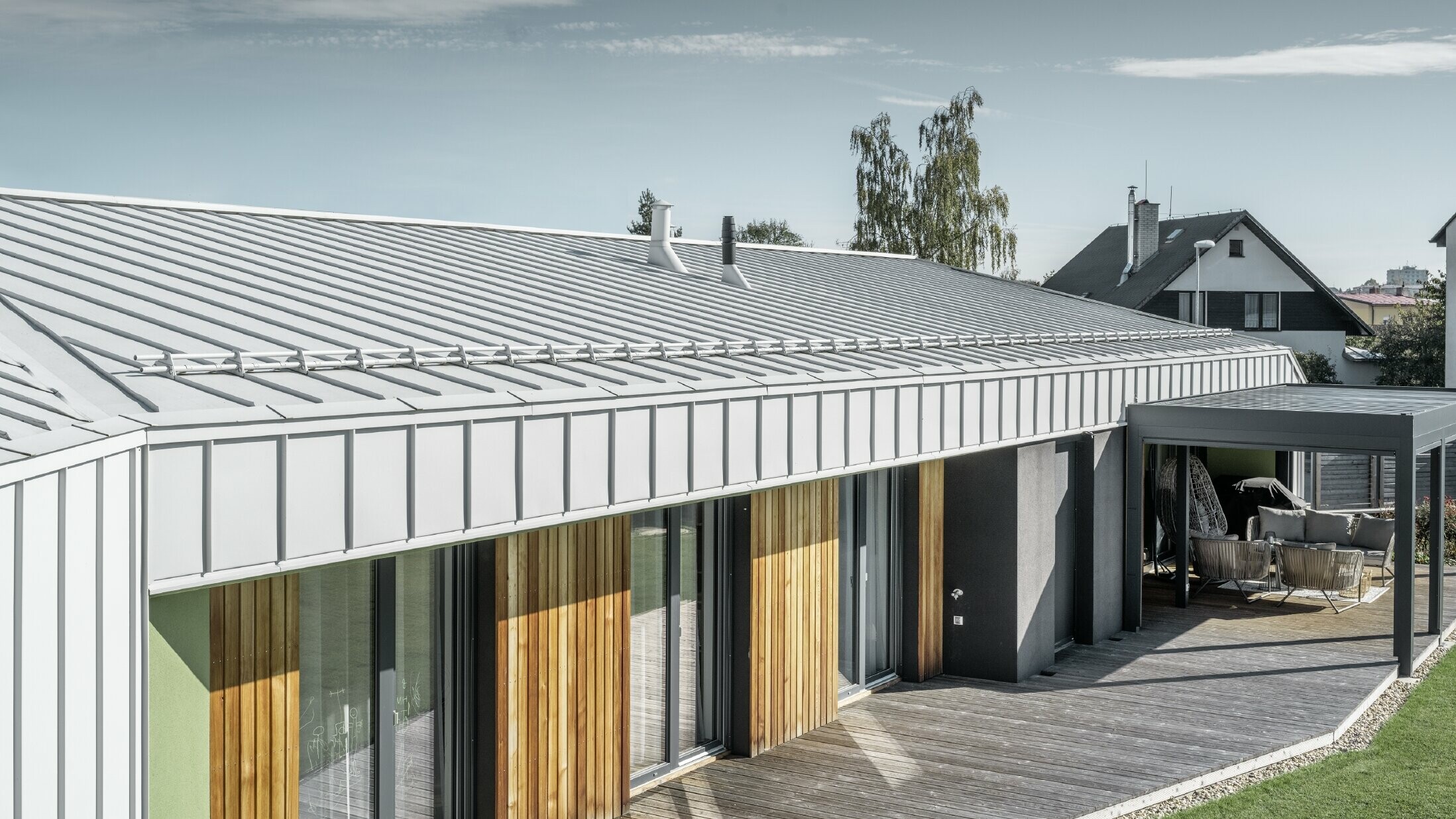 Bungalov se střechou a fasádou PREFALZ v barvě prefa bílá a dřevěná terasa