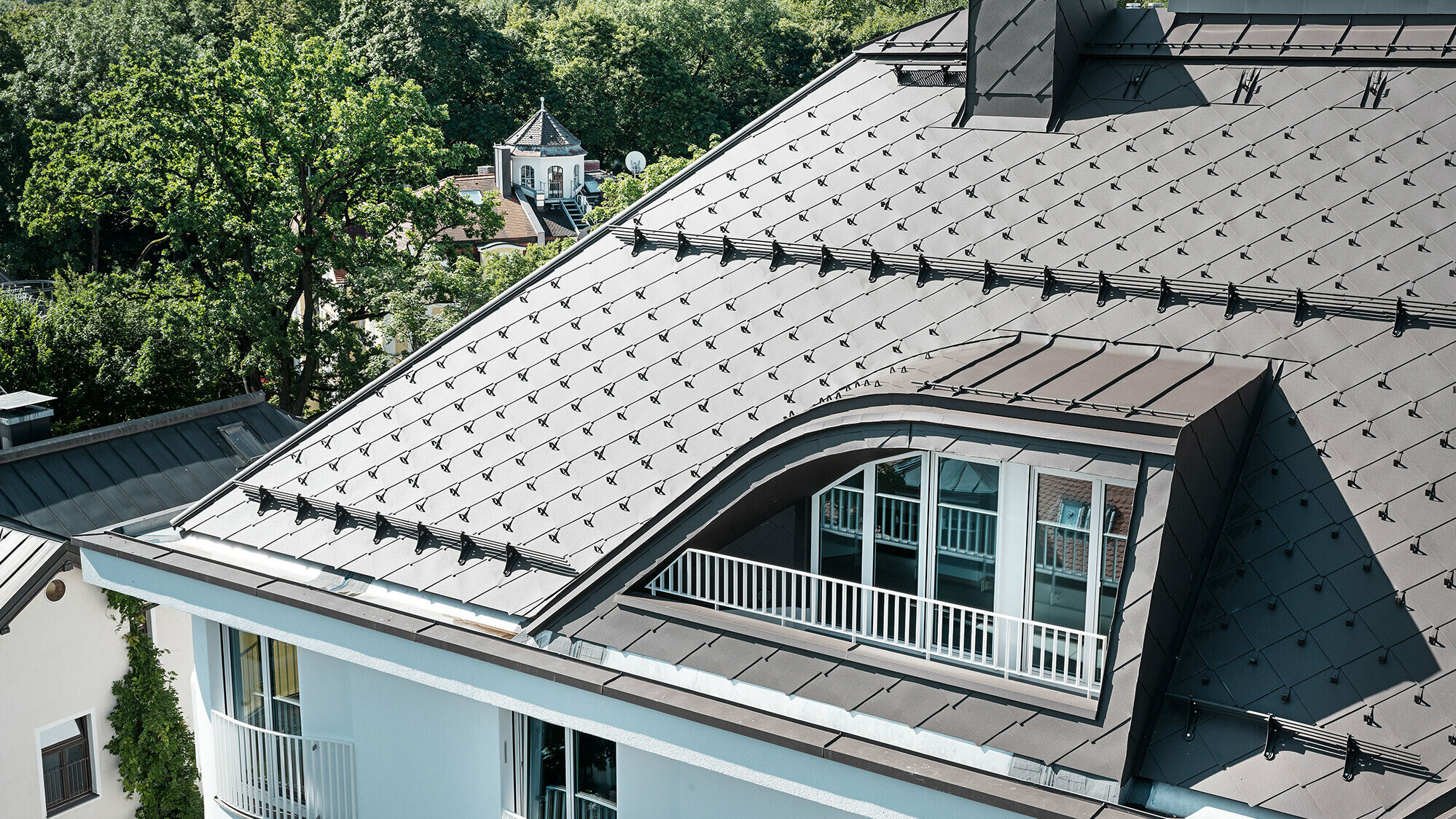 Vícegenarční dům s PREFA falcovanými šablonami 44 × 44 v hnědé barvě se sněhovými háky a sněhovými zábranami