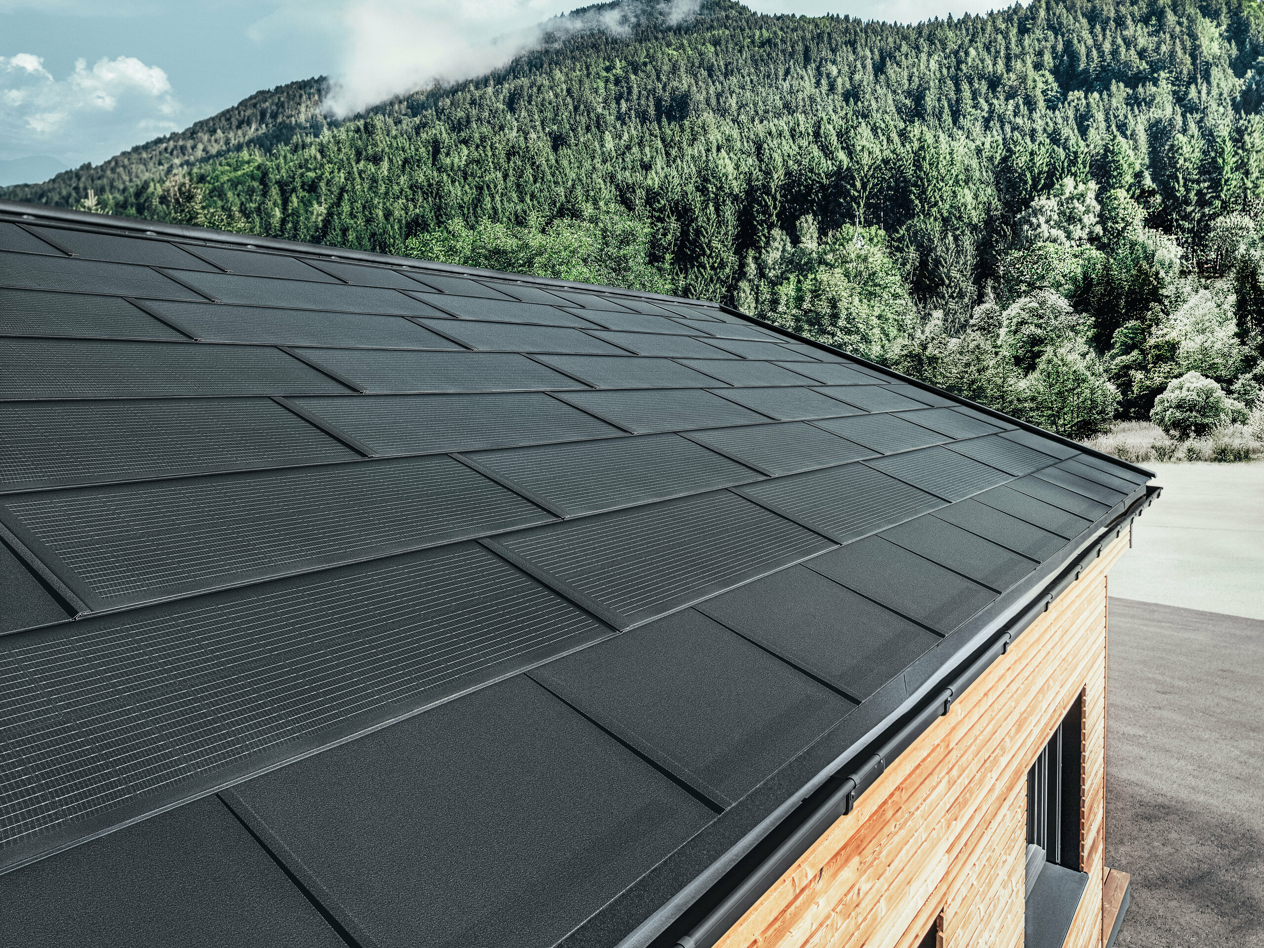 PREFA Solardachplatte in großer Ausführung kombiniert mit der Dachplatte R.16 in Schwarz, Kastenrinne und Lärchenholz-Fassade