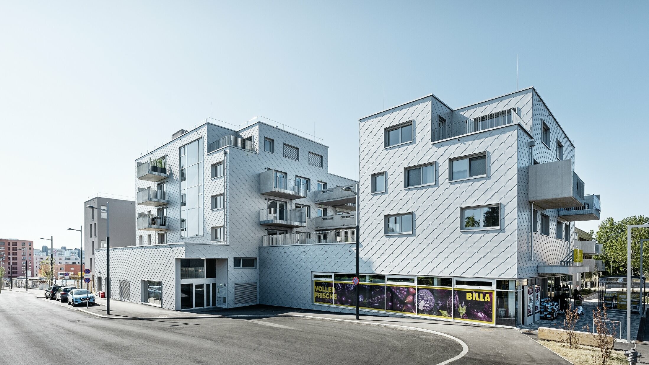 Bytové domy s plochou střechou a fasádou obloženou PREFA fasádními šablonami 44 × 44 v barvě stříbrná metalíza