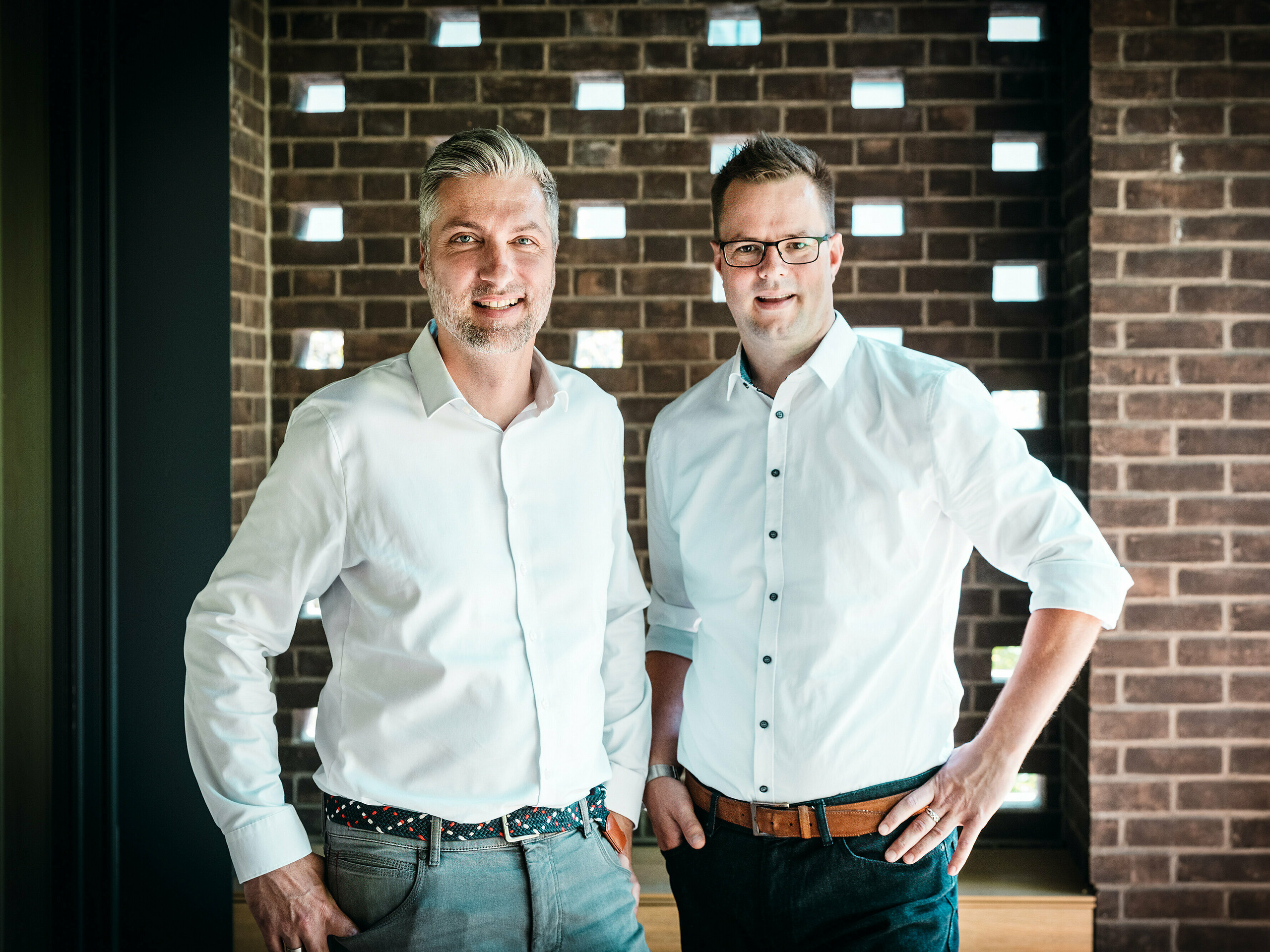 Architektonický tým ze studia A Fiúk Építész Stúdió stojí v moderním interiéru vícegenerační vily v Budapešti, která získala ocenění na veletrhu PREFARENZEN 2026. Před výraznou cihlovou zdí prezentují precizní materiálový a designový jazyk svého projektu, charakterizovaného kubickou hliníkovou střechou PREFALZ v antracitové barvě P.10. Scéna podtrhuje architektonickou odbornost, vysoce kvalitní zpracování a promyšlený výběr materiálů, kde hliník PREFA přesvědčuje svou trvanlivostí, designovou pevností a technickou precizností.