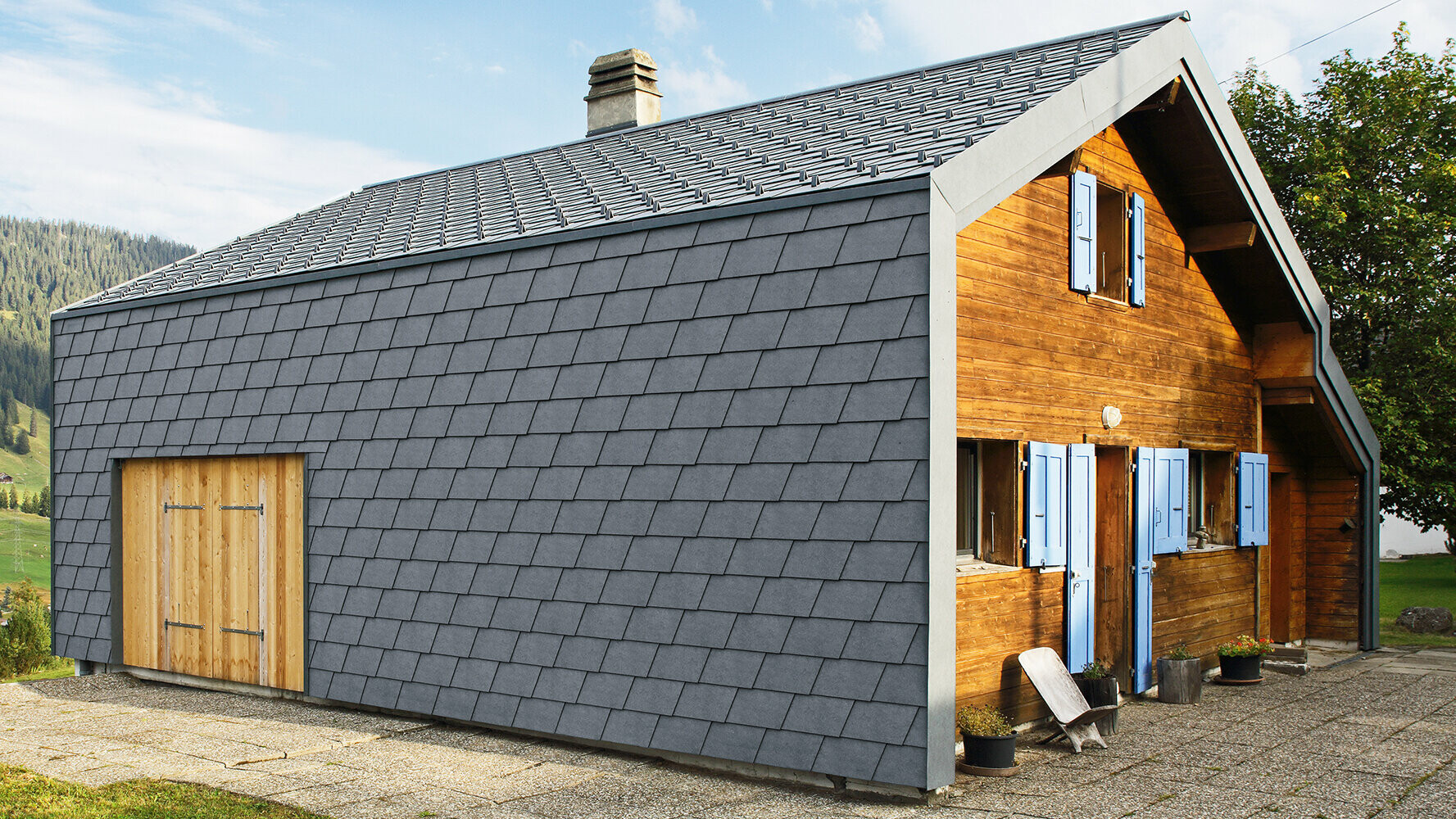 Moderní rodinný dům opláštěný PREFA fasádními šindeli v antracitové barvě a dřevěnými prvky.