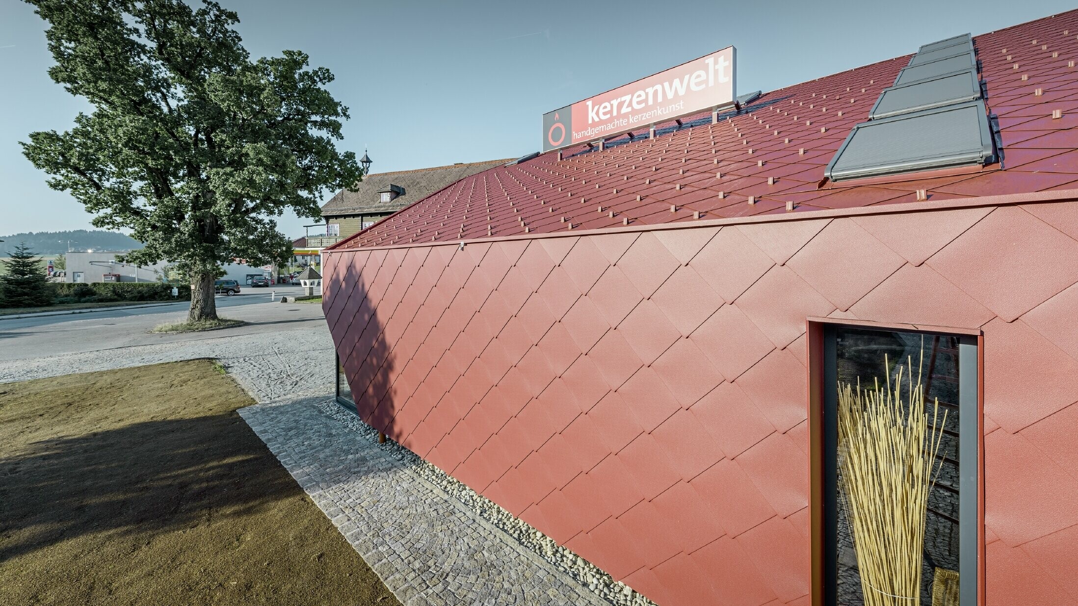 Svět svíček ve Schlägl byl kompletně pokryt šablonou PREFA. Střešní krytina a fasádní obklad byly provedeny šablonou 44 × 44 v tmavě červené barvě.